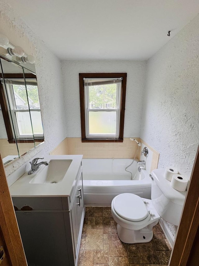1344 Mckinley Ave, Beloit, WI 53511 - full bathroom with a textured wall, toilet, vanity, a garden tub, and stone tile floors