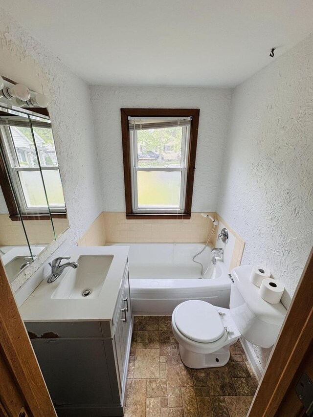 1344 Mckinley Ave, Beloit, WI 53511 - bathroom with toilet, a textured wall, vanity, a garden tub, and stone tile flooring