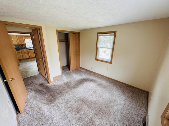 1344 Mckinley Ave, Beloit, WI 53511 - unfurnished bedroom with carpet floors, a textured ceiling, a closet, and baseboards