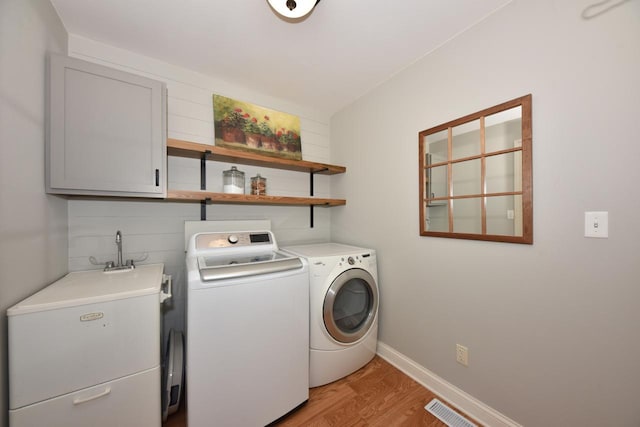 504 Sand Dr, West Bend, WI 53095 - laundry area with cabinet space, separate washer and dryer, light wood finished floors, and baseboards