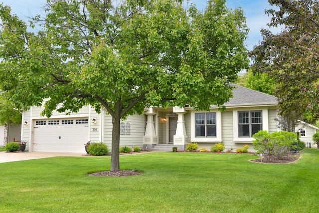 504 Sand Dr, West Bend, WI 53095 - view of property hidden behind natural elements featuring concrete driveway, a front lawn, an attached garage, and a shingled roof