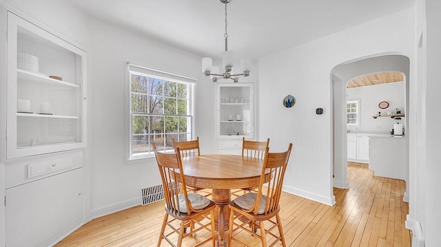 5515 Evergreen Dr, Sheboygan, WI 53081 - dining room with a chandelier, arched walkways, light wood-style floors, and baseboards