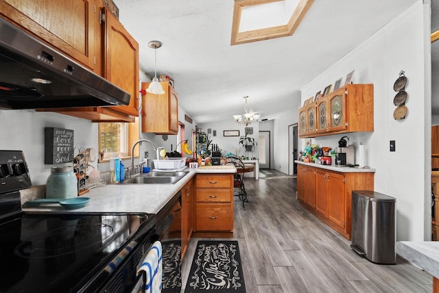 6560 US Highway 14, Arena, WI 53503 - kitchen featuring black appliances, under cabinet range hood, brown cabinetry, a chandelier, and light wood finished floors