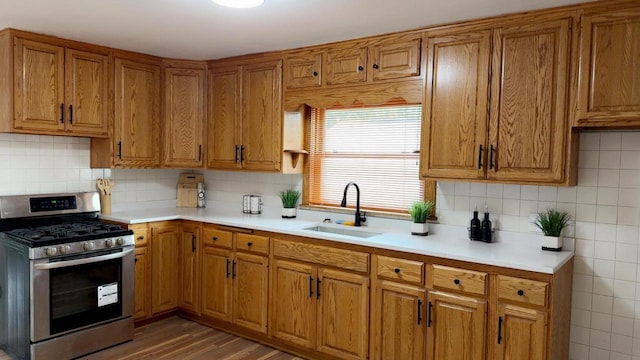 901 S 90th St, West Allis, WI 53214 - kitchen with stainless steel range with gas stovetop, a sink, brown cabinets, light countertops, and decorative backsplash