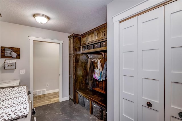 4567 Springfield Dr, Eau Claire, WI 54701 - mudroom featuring a textured ceiling, dark marble finish flooring, and baseboards