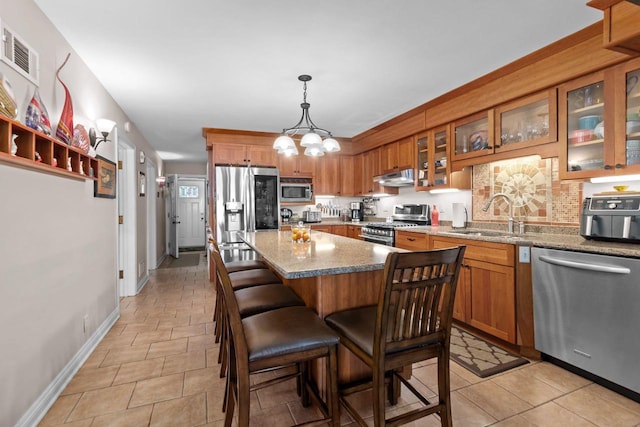 N3510 Lotus Dr, Montello, WI 53949 - kitchen featuring appliances with stainless steel finishes, a sink, under cabinet range hood, brown cabinetry, and baseboards
