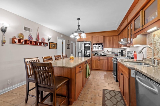 N3510 Lotus Dr, Montello, WI 53949 - kitchen featuring appliances with stainless steel finishes, a sink, brown cabinets, light stone counters, and a center island