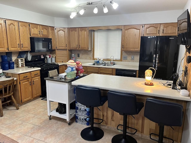 1159 Elmhurst Ln, Oshkosh, WI 54904 - kitchen featuring black appliances, a sink, a kitchen breakfast bar, decorative backsplash, and brown cabinetry