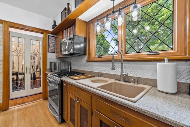 5834 W Elliott Cir, Milwaukee, WI 53208 - kitchen featuring stainless steel appliances, a sink, french doors, decorative backsplash, and brown cabinetry