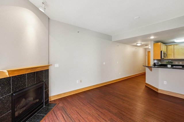 333 W Mifflin St Unit 8100, Madison, WI 53703 - unfurnished living room featuring dark wood finished floors, a tiled fireplace, and baseboards