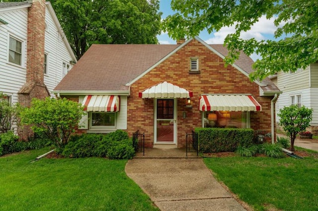 2114 S 81st St, West Allis, WI 53219 - view of front of house featuring brick siding, a front yard, roof with shingles, and a chimney