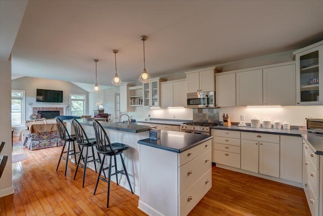 963 W Highland St, Whitewater, WI 53190 - kitchen featuring appliances with stainless steel finishes, hardwood / wood-style floors, dark countertops, white cabinetry, and a kitchen breakfast bar