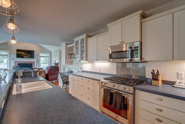 963 W Highland St, Whitewater, WI 53190 - kitchen with stainless steel appliances, a sink, a brick fireplace, dark countertops, and open floor plan