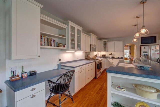963 W Highland St, Whitewater, WI 53190 - kitchen featuring appliances with stainless steel finishes, open shelves, a sink, arched walkways, and dark countertops