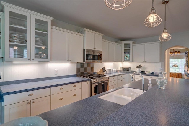 963 W Highland St, Whitewater, WI 53190 - kitchen featuring appliances with stainless steel finishes, a sink, dark countertops, arched walkways, and white cabinetry