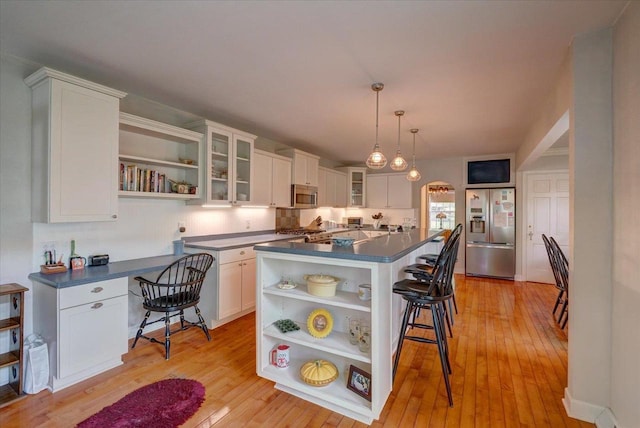 963 W Highland St, Whitewater, WI 53190 - kitchen with open shelves, stainless steel appliances, dark countertops, a breakfast bar, and white cabinets