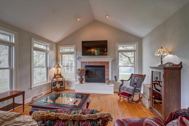 963 W Highland St, Whitewater, WI 53190 - living area featuring vaulted ceiling, hardwood / wood-style flooring, a brick fireplace, and baseboards