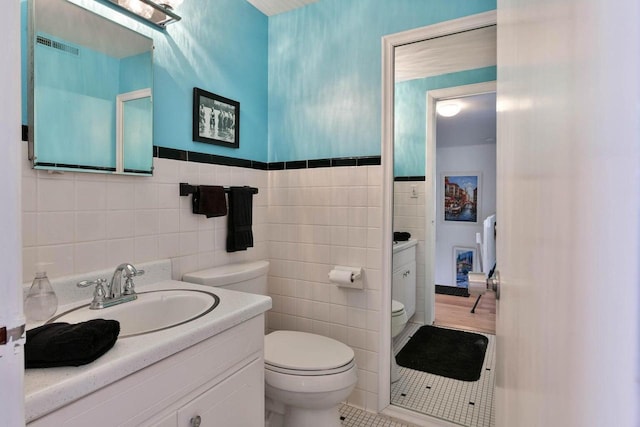 N60W39640 Mary Ln, Oconomowoc, WI 53066 - bathroom featuring toilet, tile walls, vanity, tile patterned floors, and a wainscoted wall