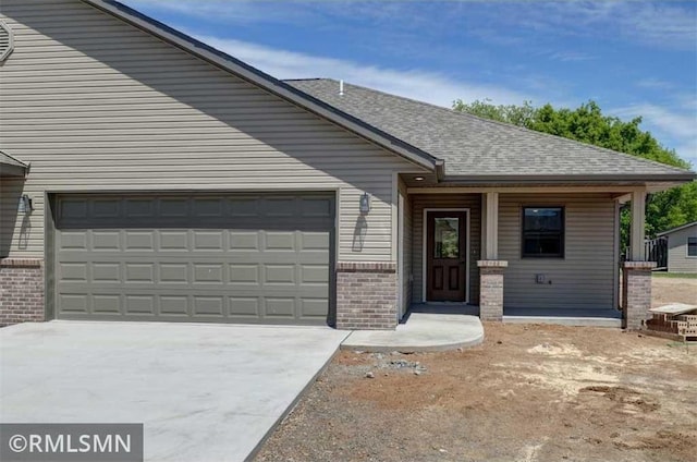 620 Pondhurst Dr, Amery, WI 54001 - view of front of house featuring brick siding, a garage, driveway, covered porch, and roof with shingles