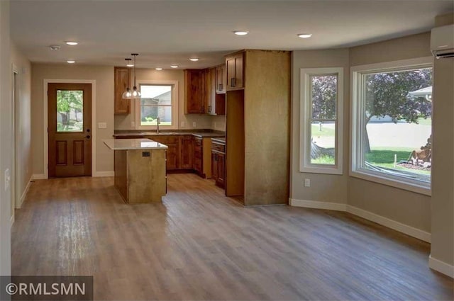 622 Pondhurst Dr, Amery, WI 54001 - kitchen featuring a wall mounted air conditioner, brown cabinetry, light wood-style flooring, pendant lighting, and recessed lighting
