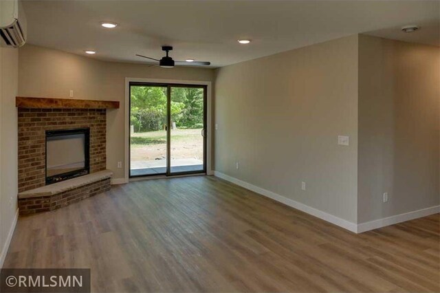 622 Pondhurst Dr, Amery, WI 54001 - unfurnished living room featuring a wall unit AC, wood finished floors, a ceiling fan, a fireplace, and recessed lighting