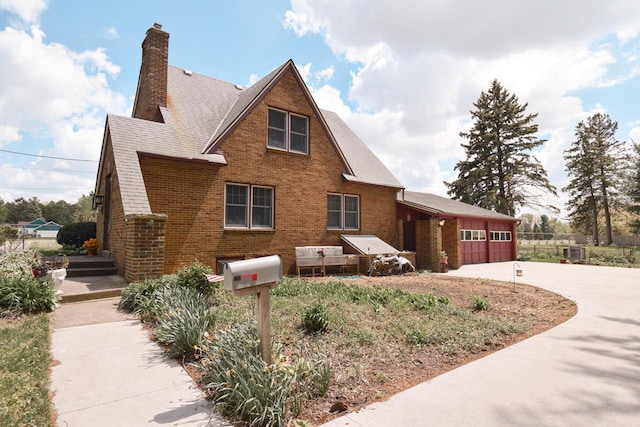 1139 W Highland St, Whitewater, WI 53190 - view of front of house with brick siding, a chimney, driveway, and an attached garage