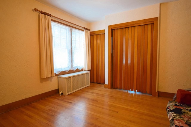 1139 W Highland St, Whitewater, WI 53190 - unfurnished bedroom with radiator heating unit, wood finished floors, a textured wall, and baseboards