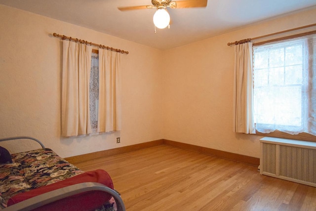 1139 W Highland St, Whitewater, WI 53190 - bedroom with radiator, light wood-style flooring, baseboards, and ceiling fan