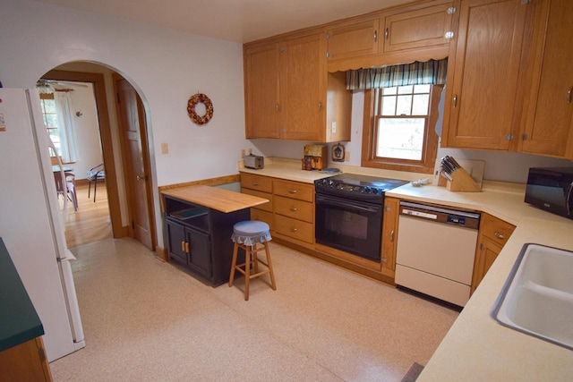 1139 W Highland St, Whitewater, WI 53190 - kitchen featuring black appliances, arched walkways, light countertops, a sink, and brown cabinets