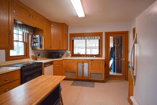 1139 W Highland St, Whitewater, WI 53190 - kitchen with black appliances, a sink, brown cabinetry, butcher block counters, and light colored carpet