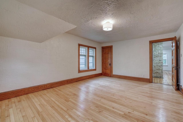 1551 N 50th St, Milwaukee, WI 53208 - empty room featuring a textured ceiling, baseboards, light wood-style flooring, and a textured wall