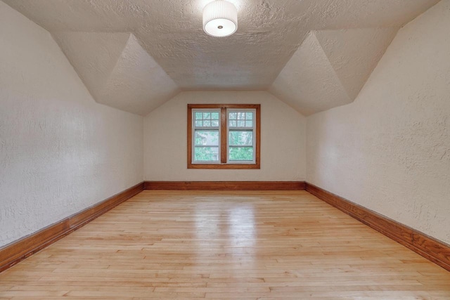 1551 N 50th St, Milwaukee, WI 53208 - bonus room with light wood-type flooring, a textured ceiling, a textured wall, lofted ceiling, and baseboards