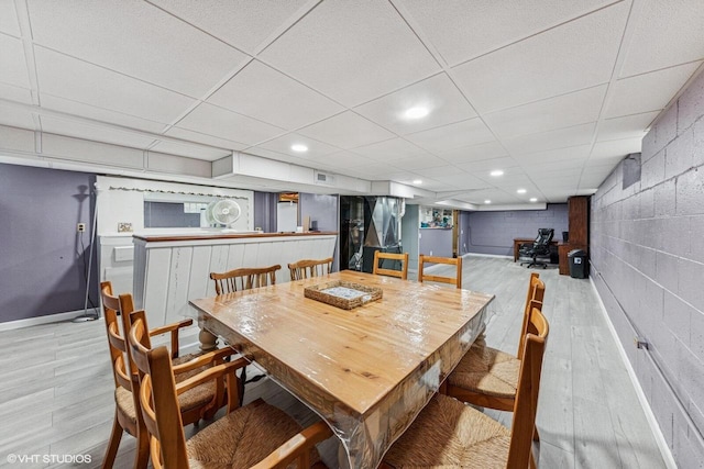 2300 W Lawn Ave, Racine, WI 53405 - dining room featuring light wood-style floors, concrete block wall, baseboards, and a paneled ceiling