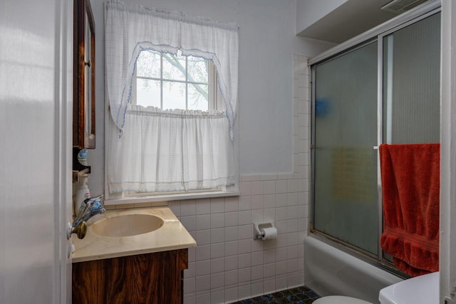 7312 5th Ave, Kenosha, WI 53143 - bathroom with vanity, toilet, tile walls, combined bath / shower with glass door, and wainscoting