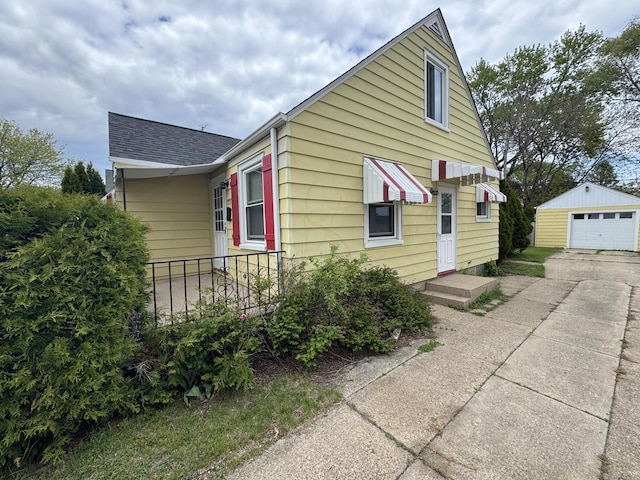 7715 18th Ave, Kenosha, WI 53143 - view of front of home featuring an outdoor structure, concrete driveway, a detached garage, and roof with shingles