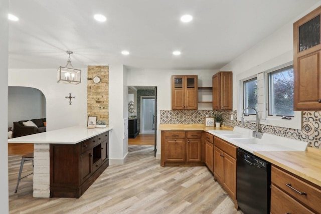 N62W23527 Sliver Spring Dr, Sussex, WI 53089 - kitchen with dishwasher, a breakfast bar area, backsplash, a peninsula, and light wood-type flooring