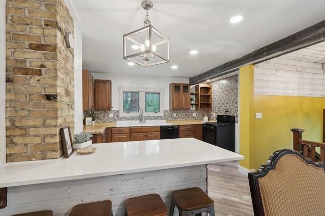 N62W23527 Sliver Spring Dr, Sussex, WI 53089 - kitchen with black appliances, a peninsula, light wood-style flooring, decorative backsplash, and a kitchen breakfast bar