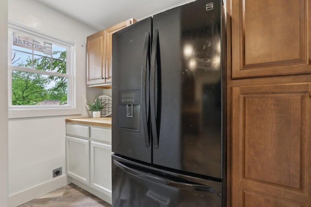 N62W23527 Sliver Spring Dr, Sussex, WI 53089 - kitchen with black fridge with ice dispenser, baseboards, light countertops, white cabinets, and light wood-type flooring