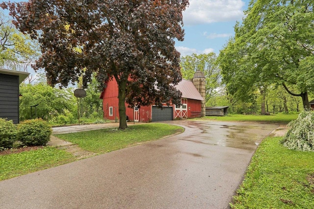 N62W23527 Sliver Spring Dr, Sussex, WI 53089 - view of front of house featuring a barn, asphalt driveway, a chimney, an outbuilding, and a front lawn