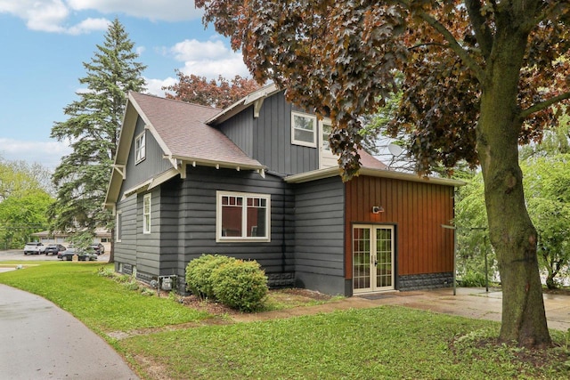 N62W23527 Sliver Spring Dr, Sussex, WI 53089 - view of side of property with french doors, a lawn, a shingled roof, and board and batten siding