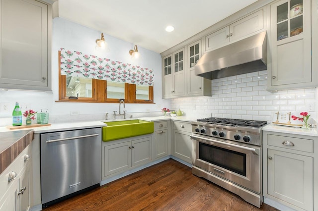 529 N 68th St, Wauwatosa, WI 53213 - kitchen featuring appliances with stainless steel finishes, under cabinet range hood, a sink, dark wood finished floors, and backsplash