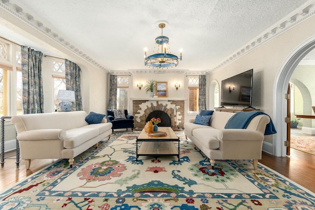 529 N 68th St, Wauwatosa, WI 53213 - living area with arched walkways, wood finished floors, a chandelier, a brick fireplace, and a textured ceiling