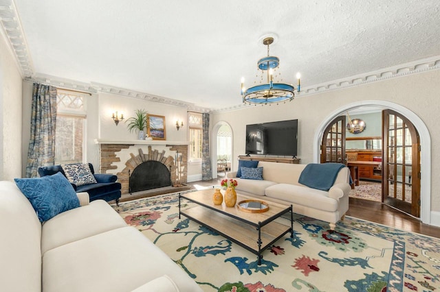 529 N 68th St, Wauwatosa, WI 53213 - living area featuring a chandelier, wood finished floors, arched walkways, a brick fireplace, and baseboards