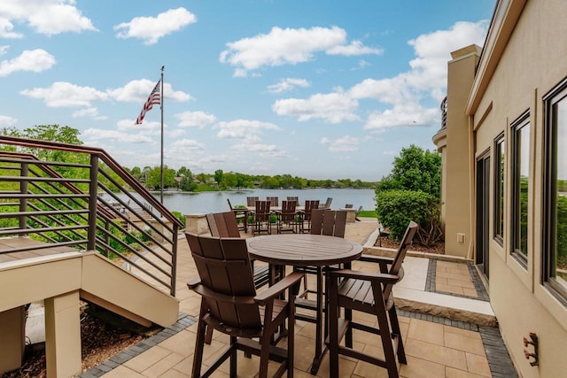 N49W35398 Wisconsin Ave, Oconomowoc, WI 53066 - view of patio / terrace featuring a water view, outdoor dining area, and stairway
