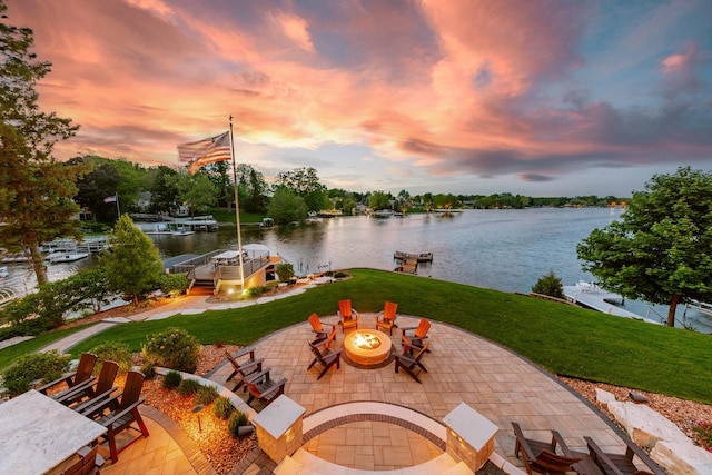 N49W35398 Wisconsin Ave, Oconomowoc, WI 53066 - patio terrace at dusk featuring a patio, a boat dock, a water view, a fire pit, and a lawn