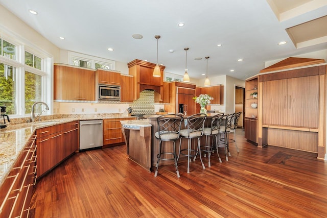 N49W35398 Wisconsin Ave, Oconomowoc, WI 53066 - kitchen with built in appliances, dark wood-style flooring, a sink, a kitchen bar, and a center island