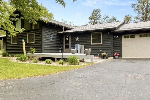 29774 Whispering Pines Rd, Lone Rock, WI 53556 - view of front facade with an attached garage, metal roof, asphalt driveway, and log veneer siding