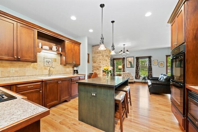 W522 Highland Rd, Genoa City, WI 53128 - kitchen featuring open floor plan, light wood finished floors, a kitchen breakfast bar, a sink, and tasteful backsplash