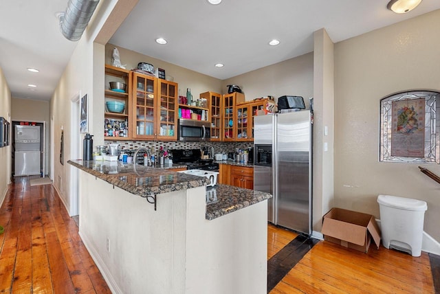 518-520 E Glover Ave, Milwaukee, WI 53212 - kitchen featuring stainless steel appliances, brown cabinetry, a peninsula, dark stone counters, and light wood-type flooring