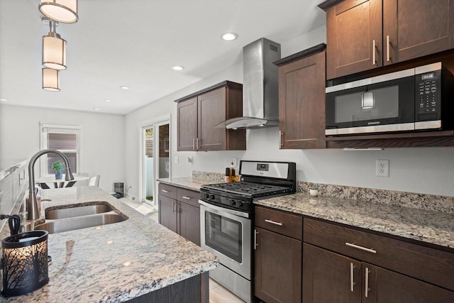915 E Ohio Ave, Milwaukee, WI 53207 - kitchen with appliances with stainless steel finishes, wall chimney exhaust hood, a sink, hanging light fixtures, and light stone countertops